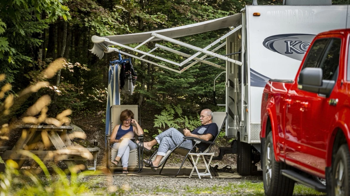 Un couple qui lise un livre sous le auvent de leur roulotte.