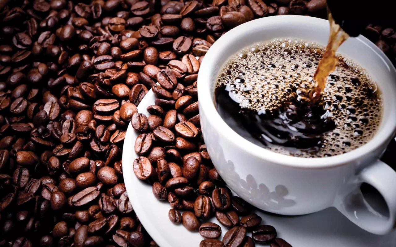 vue gros plan d'une tasse de café entourée de grains de café