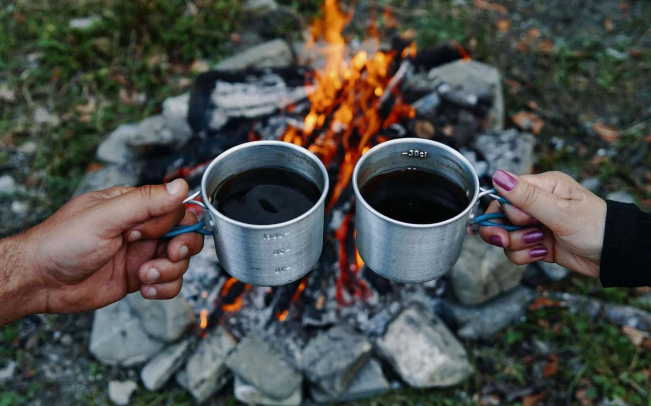 vue de deux tasses de café au dessus d'un feu de camp