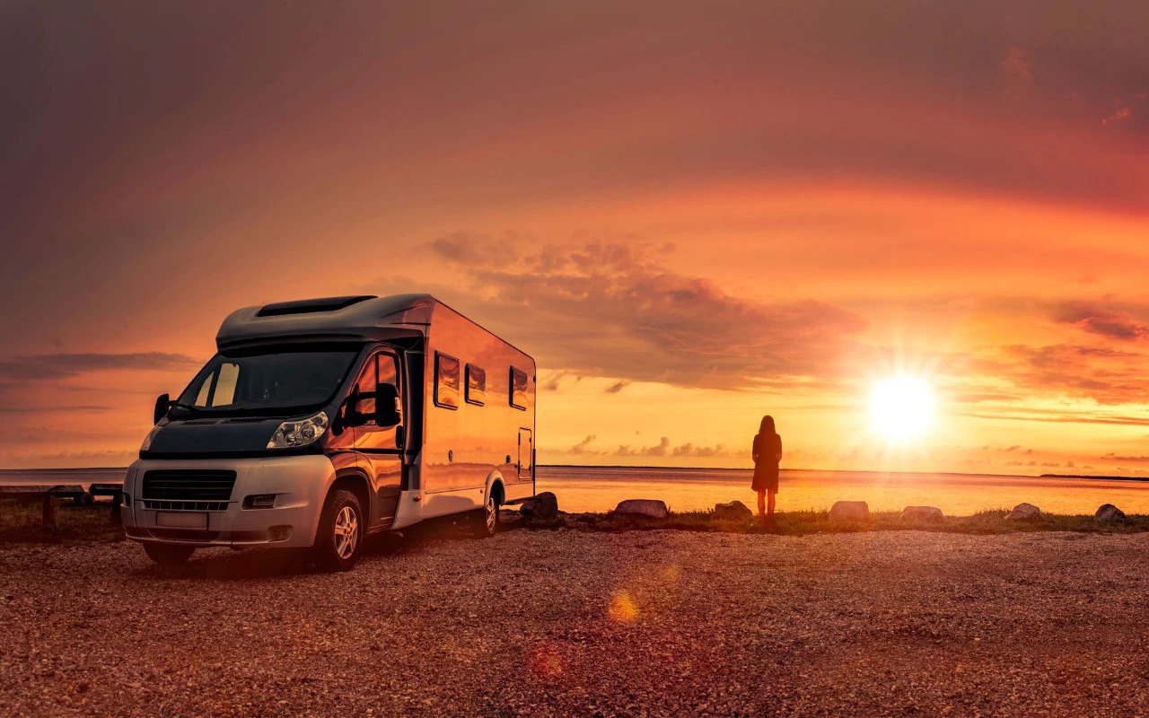 vue d'une roulotte et sa conductrice sur le bord de l'eau au crépuscule