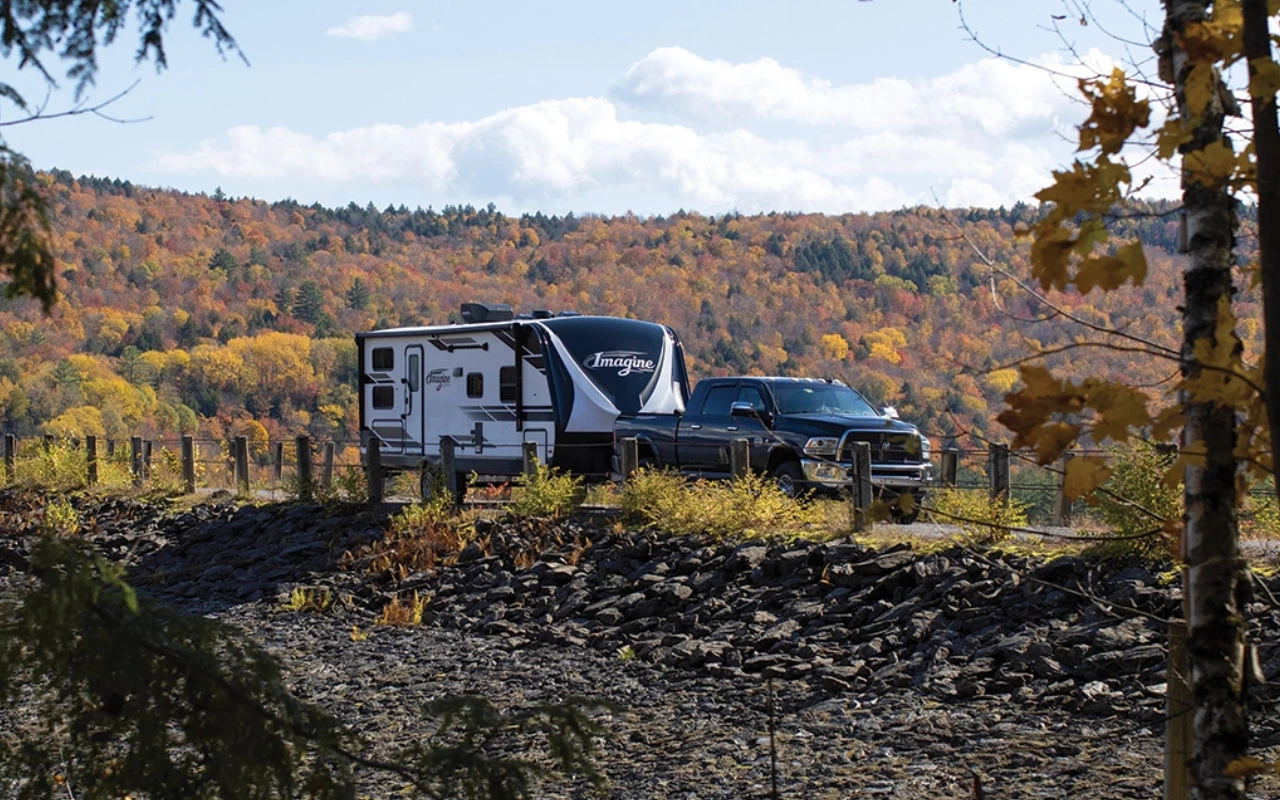 vue d'une roulotte de type '5th wheel' sur une route de campagne en automne